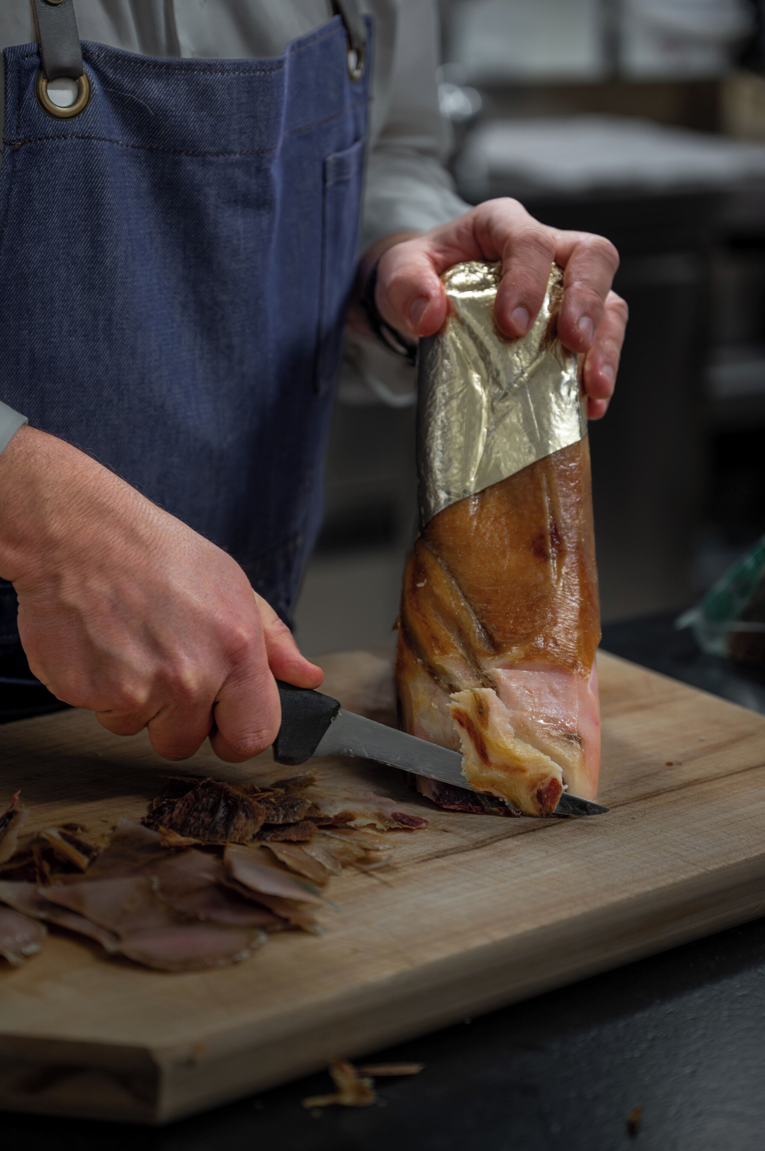 Una persona cortando un trozo grande de carne en una tabla de madera.