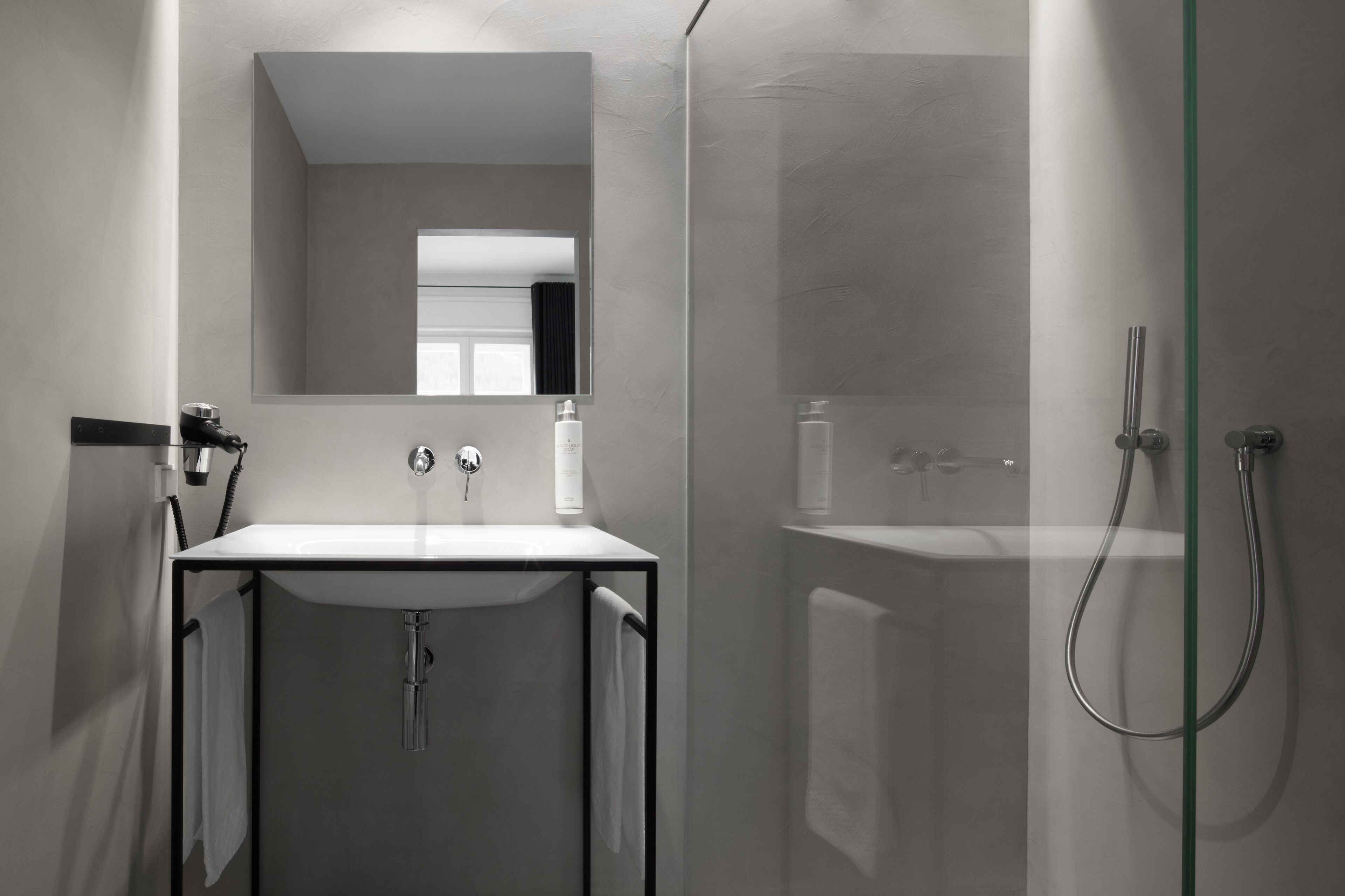 Un bagno moderno con doccia vetrata, un lavandino bianco e uno specchio sopra il lavandino.