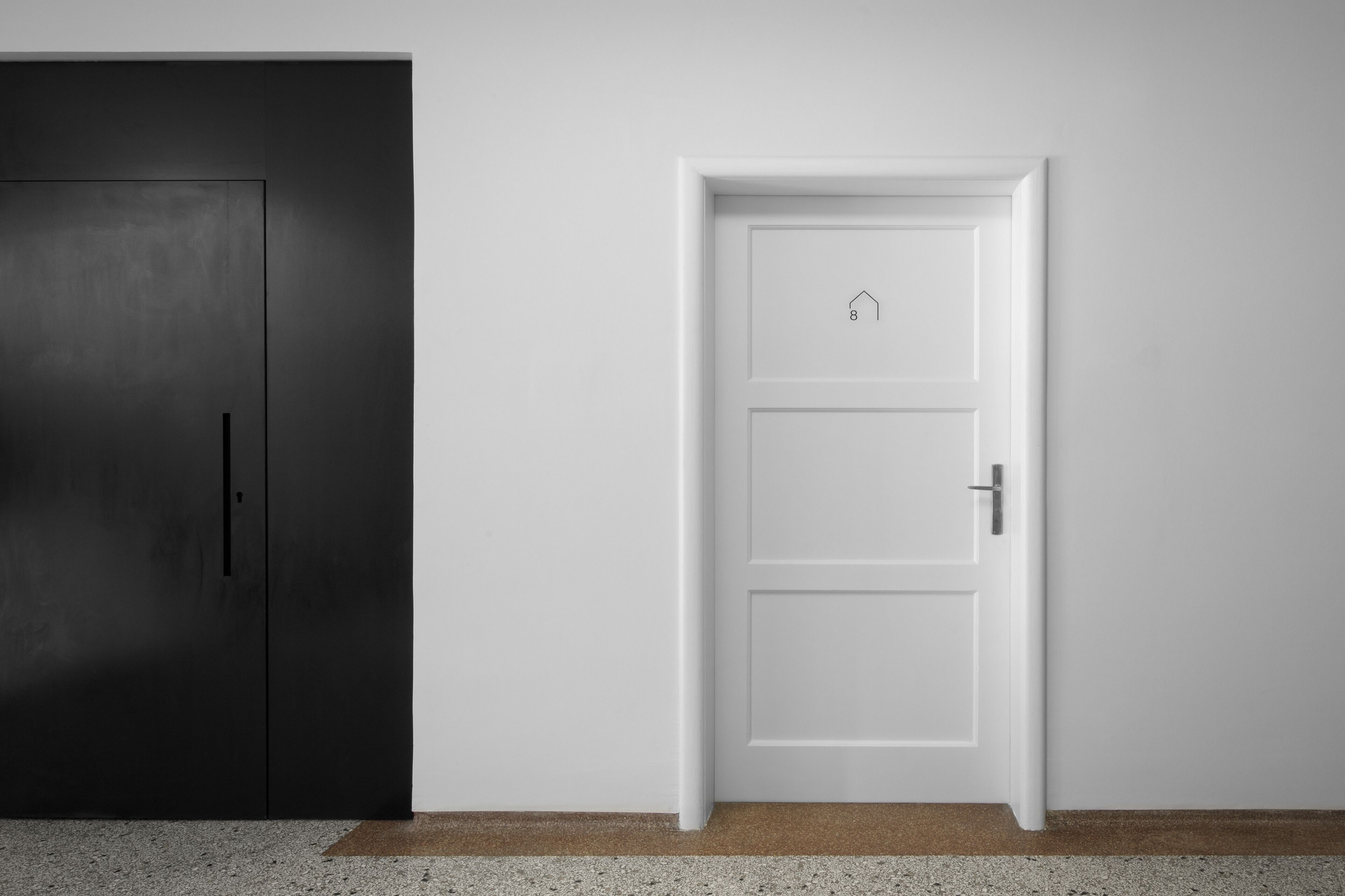 Habitación con un armario de color oscuro y una puerta blanca con el icono de una casa, que indica un número de habitación específico.