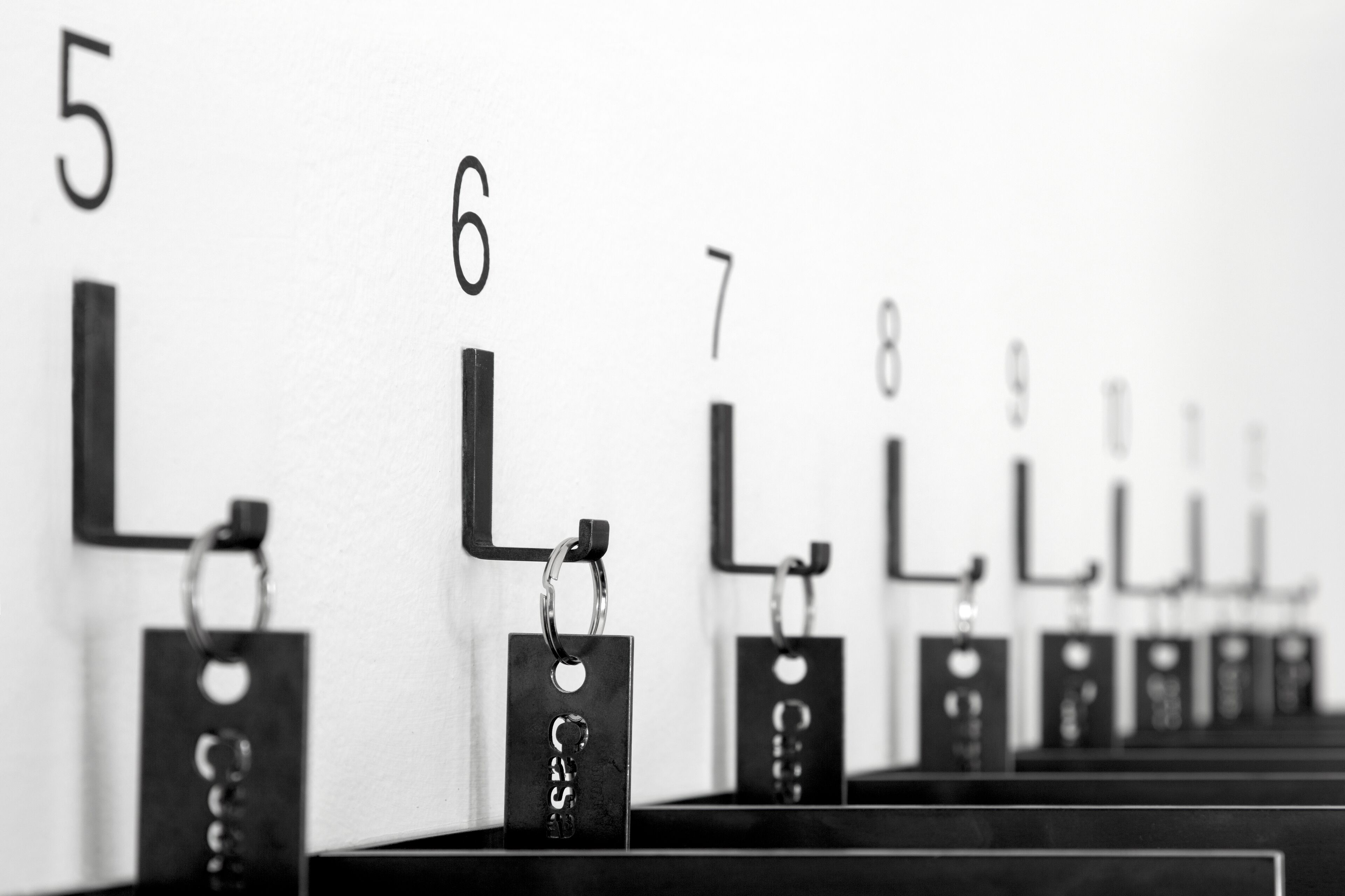 A row of numbered lockers, each with a metal ring and a keyhole, against a white wall.
