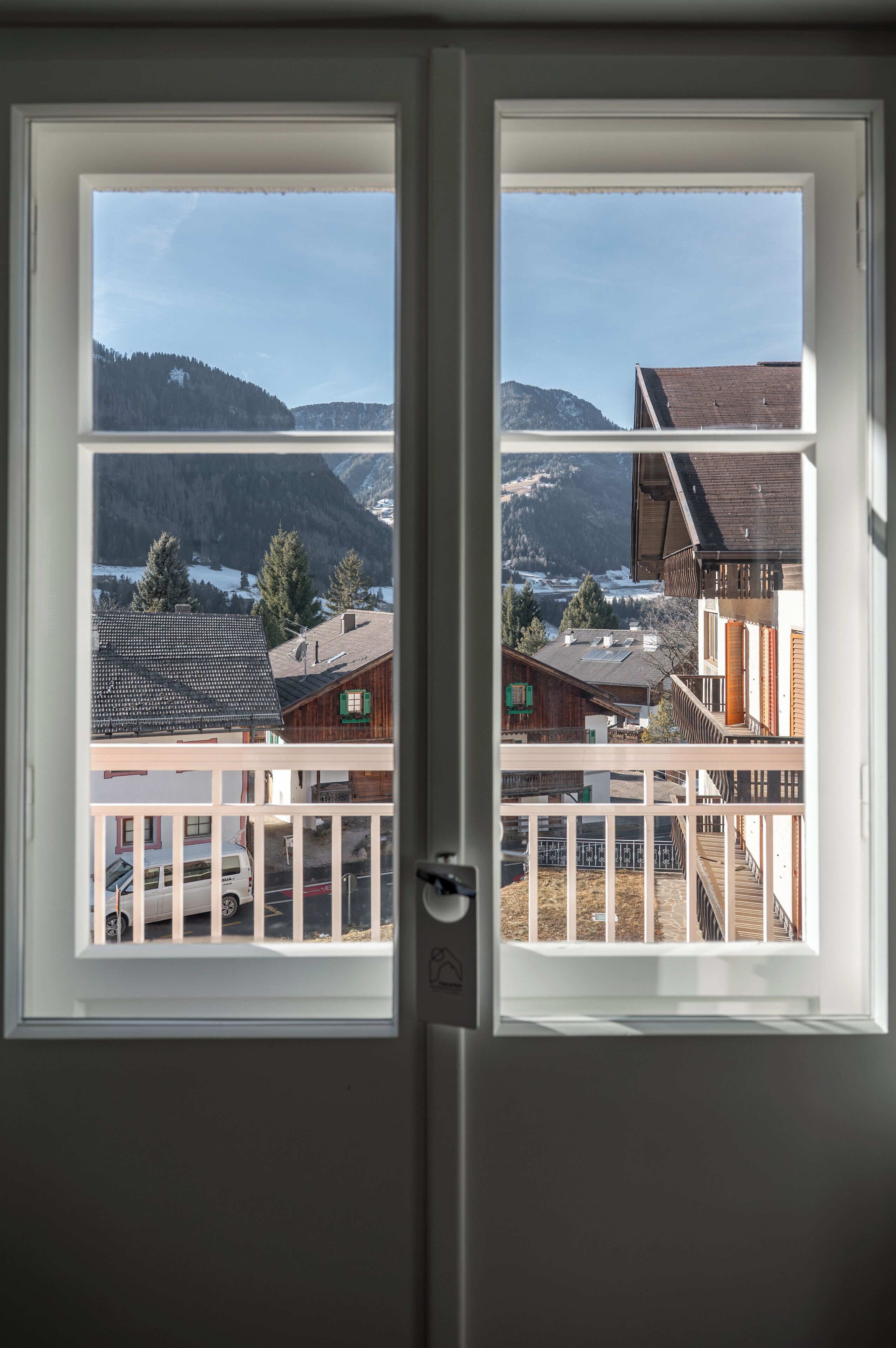Una puerta con dos ventanas, cada una mostrando vistas de un paisaje montañoso con edificios.