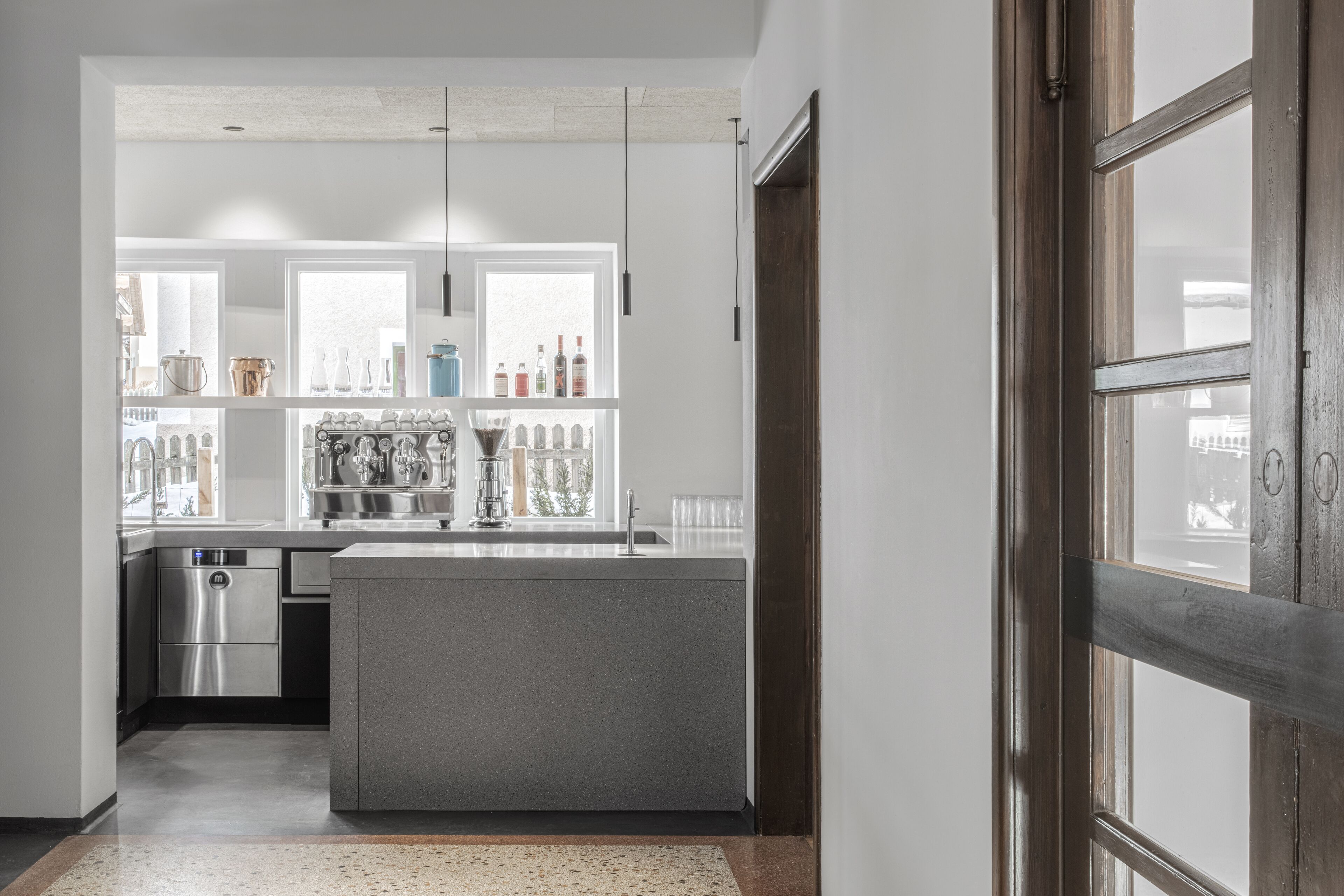 Una cocina moderna con una isla central, electrodomésticos de acero inoxidable y vistas amplias a través de grandes ventanales.
