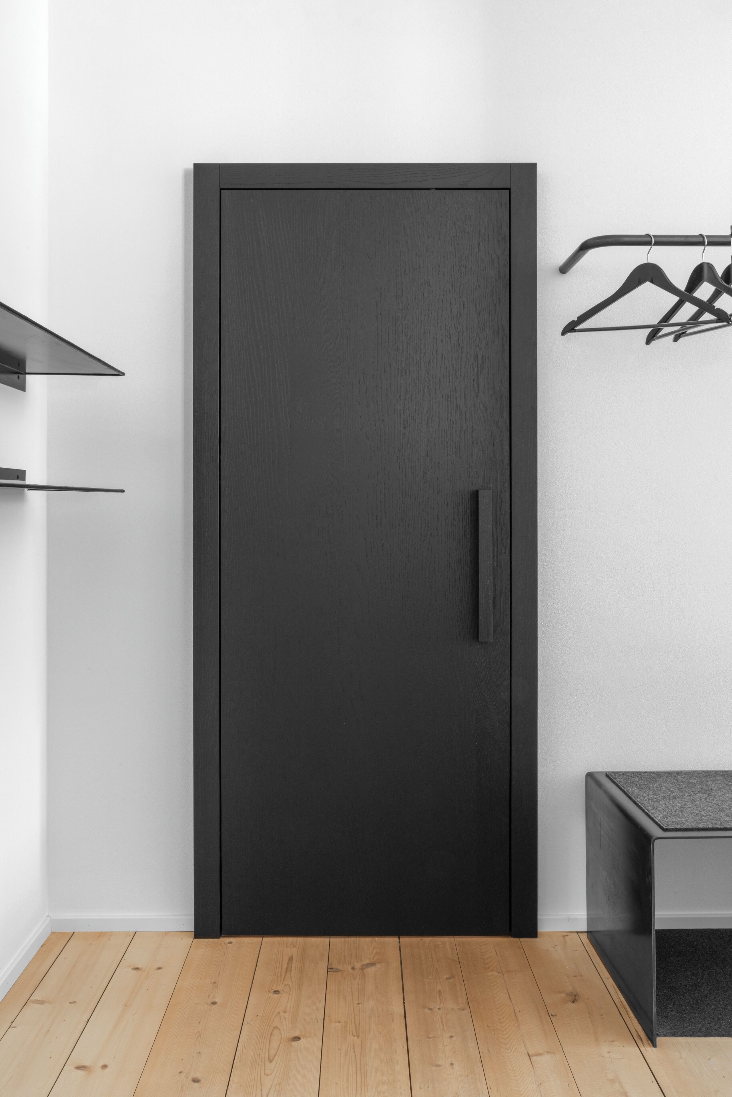 Une chambre moderne avec une armoire en bois foncé, une petite table et un portant à vêtements adossé au mur.