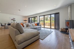 Relax in this stylish living room with a large sofa, fireplace, and dining area.