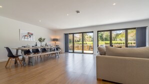A spacious living area with a large window, a dining table with chairs, and a sofa.