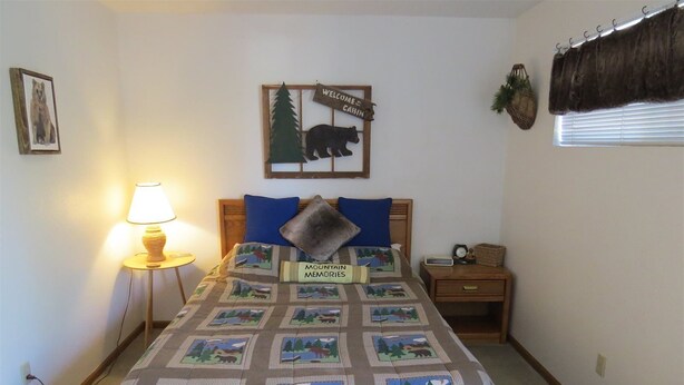 Ein Schlafzimmer mit einem Bett, einem Nachttisch, einer Lampe, einer Wanduhr und einem Willkommensschild.