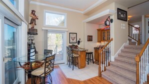 A dining area with a glass table, chairs, and a bar area with stools. There is a staircase leading to another level. - Bella Lago House (Osage Beach)
