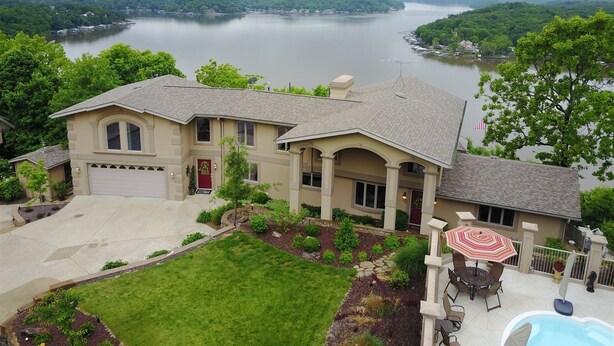 A two-story house with a large front yard, a swimming pool, and a view of a lake. - Bella Lago House (Osage Beach)