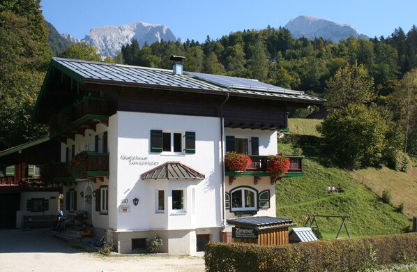 A two-story building with a sloped roof, balconies with flower boxes, and a sign indicating it is a restaurant.