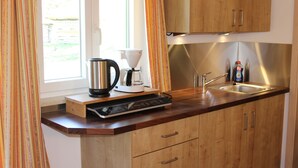 Eine Küche mit Holzausstattung, einem Edelstahlspülbecken, einer Kaffeemaschine und einem Wasserkocher.