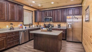 Una cocina moderna con armarios de madera oscura, electrodomésticos de acero inoxidable y una isla con encimera de granito.