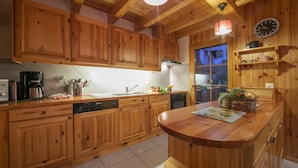 A wooden kitchen with a central island, wooden cabinets, a coffee maker, and a clock on the wall.