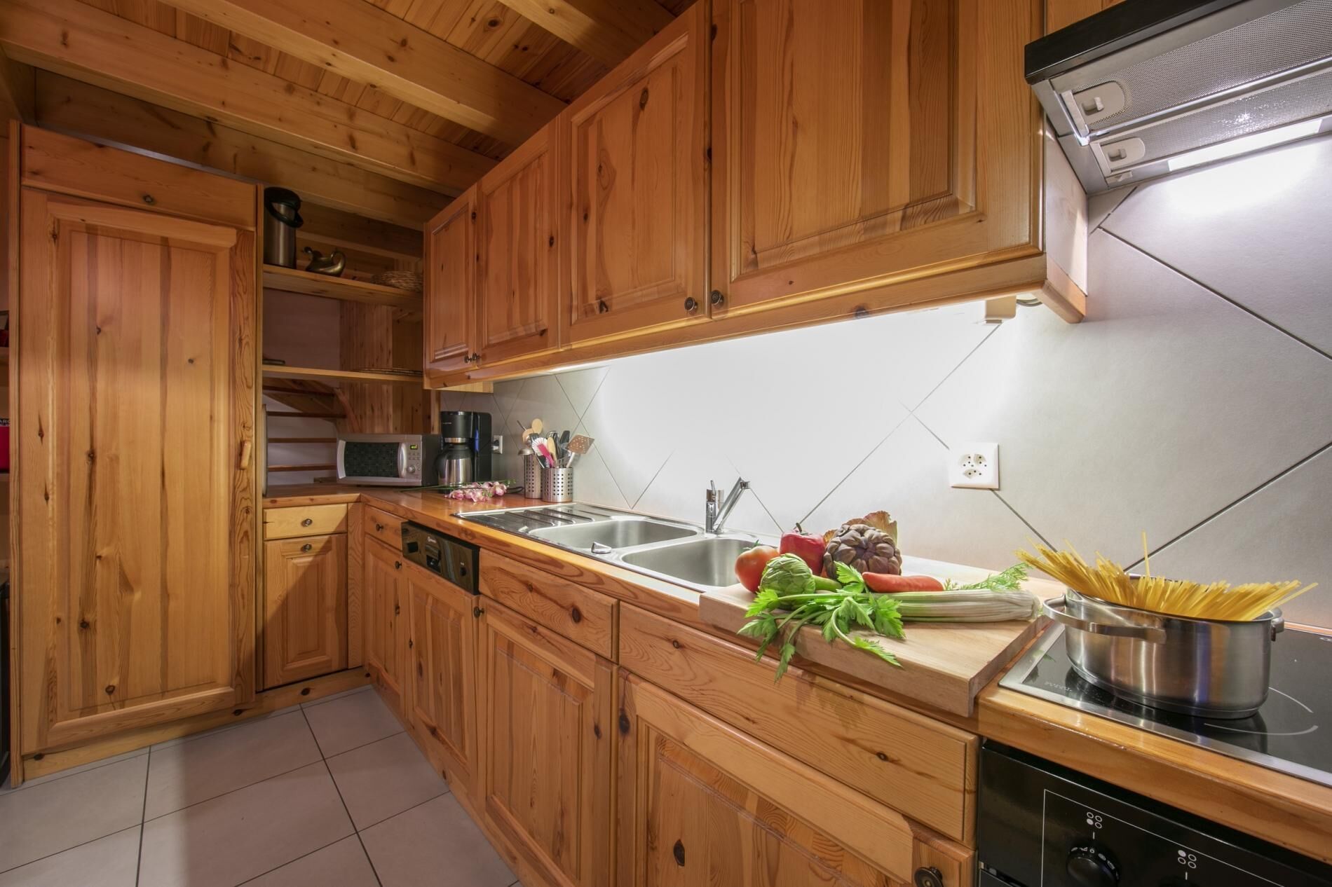 Una cocina con armarios de madera, un lavamanos de acero inoxidable, un microondas y una estufa.