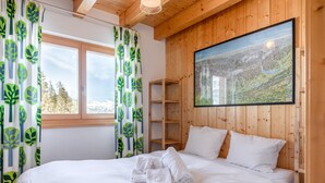 A bedroom with a bed, white bedding, a wooden headboard, a window with curtains, and a painting on the wall. - Chalet Belle Roche Recently Renovated Jacuzzi (Riddes)