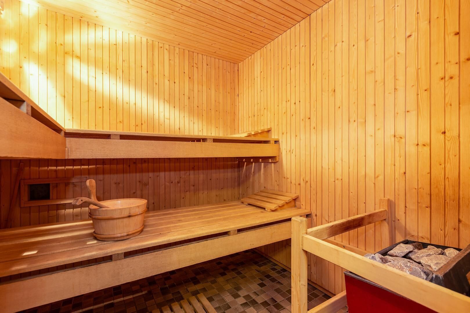 Un sauna en bois avec des bancs et un seau en bois.