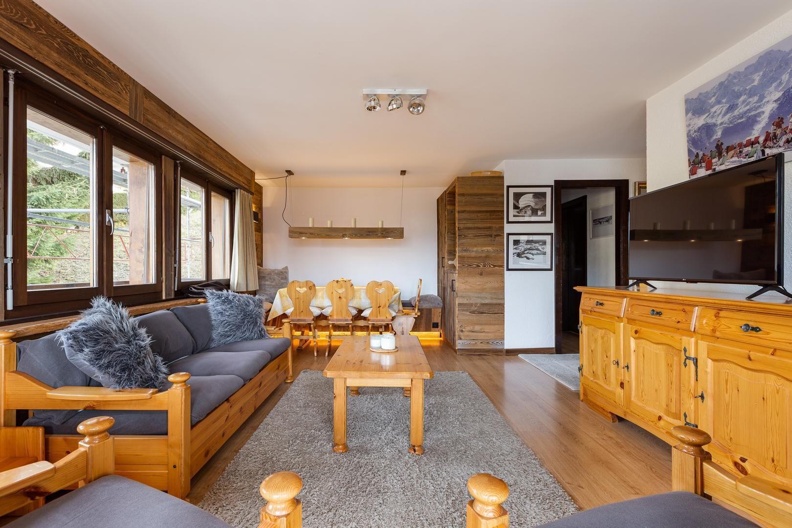 A cozy living room with a sofa, chairs, a wooden coffee table, and a TV.