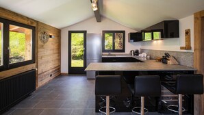 A modern kitchen with a central island, bar stools, a refrigerator, and a sink. - Chalet Lupin (Riddes)