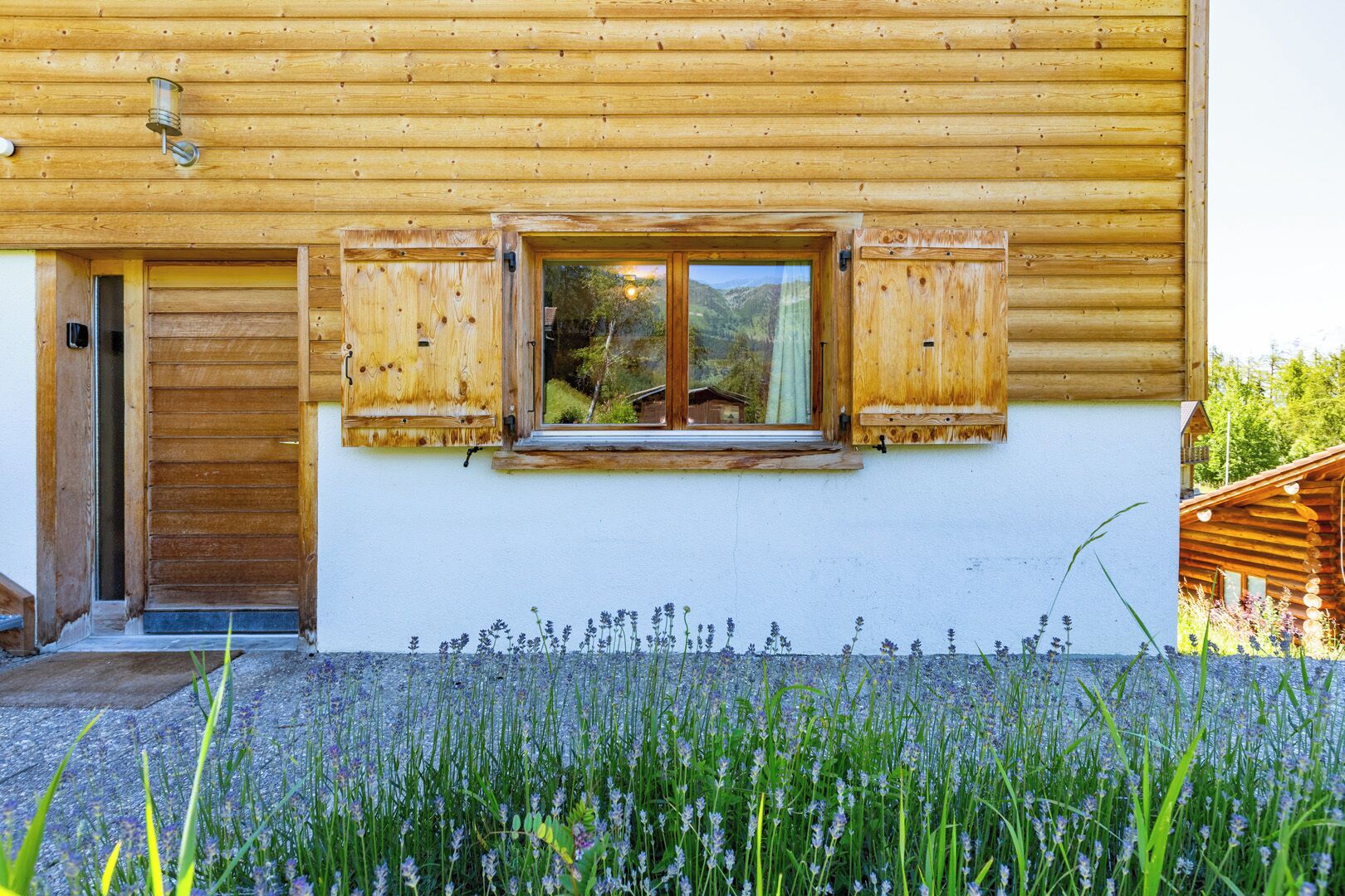 Eine Holzhütte mit Fenster und Tür, umgeben von einem Lavendelgarten.