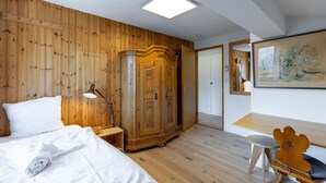 Hotellihuone, jossa on puupanelilla verhoiltu seinä, valkoisilla lakanoilla varustettu sänky, työpöytä ja tuoli, vaatekaappi sekä taulu seinällä.