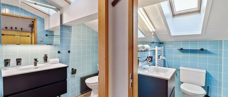 A modern bathroom with skylights, a black vanity, and a white sink.