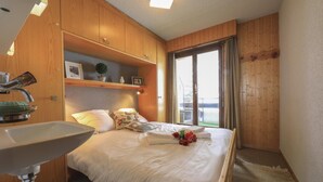Un dormitorio con cama, armario de madera, lavamanos y ventana con vistas.