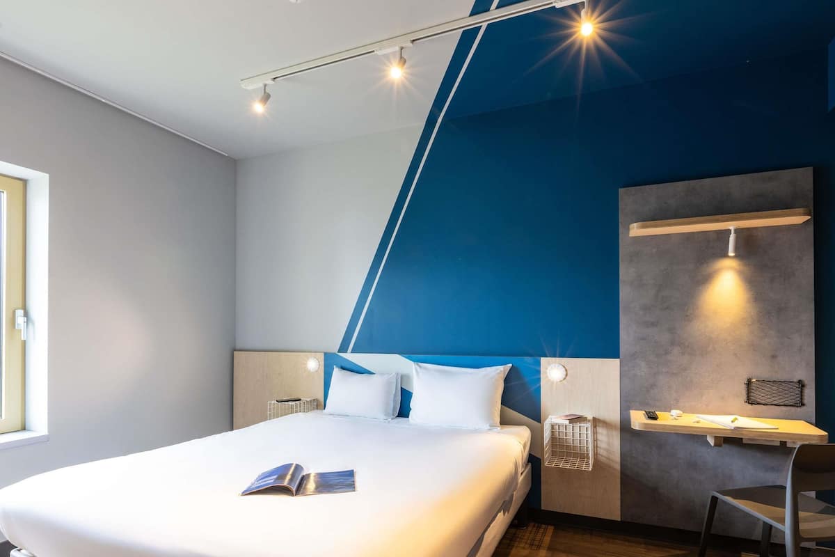 Ett modernt hotellrum med en stor säng, ett skrivbord och en stol.