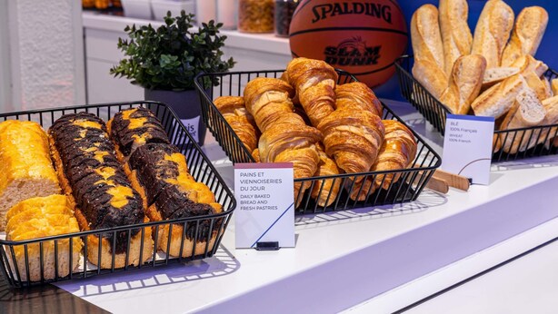 Exposição de doces e pães numa padaria, incluindo pão e pastelaria.