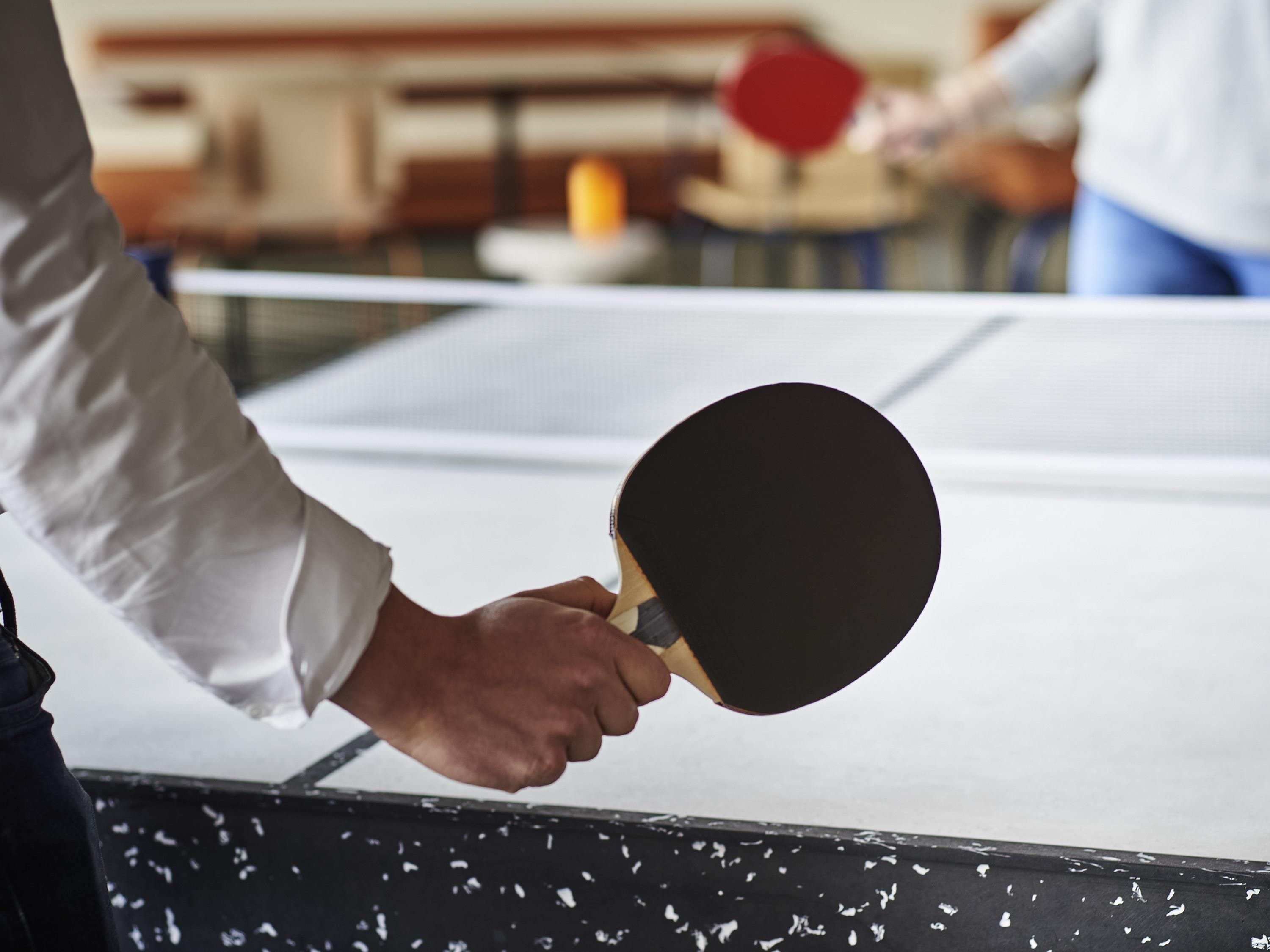 A table tennis table with a paddle in hand.