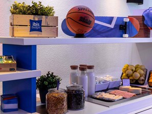 A breakfast buffet with various food items, a basketball, and a plant on the counter.