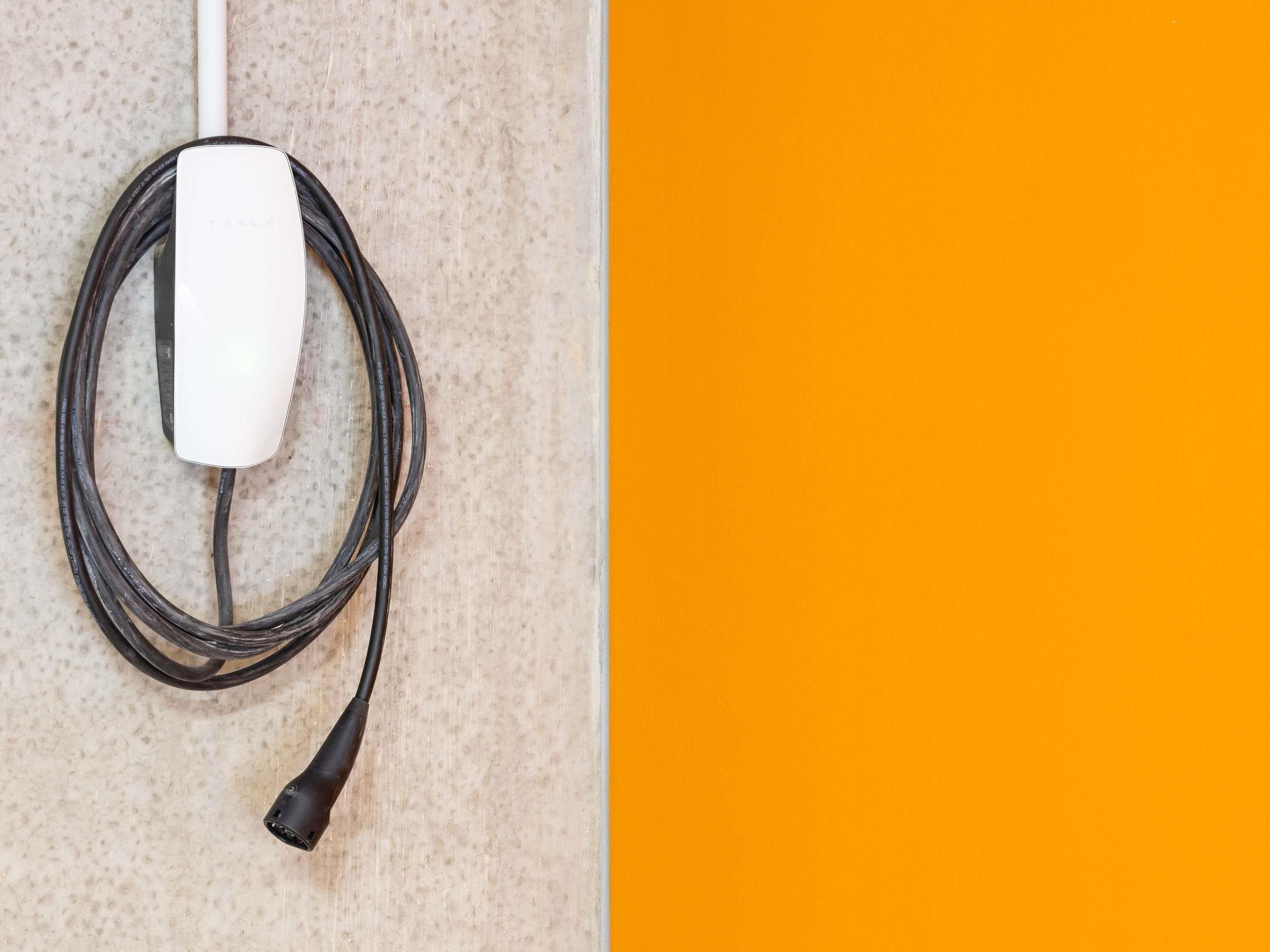Ein weißes Tesla Ladekabel liegt in einer gewellten Textur.
