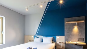 A modern hotel room with a large bed, a desk, and a chair.
