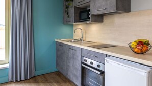 Uma cozinha moderna com armários cinza, uma pia de aço inoxidável, forno e micro-ondas.