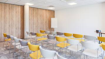 A conference room with rows of chairs, a whiteboard, and a projector on the ceiling.
