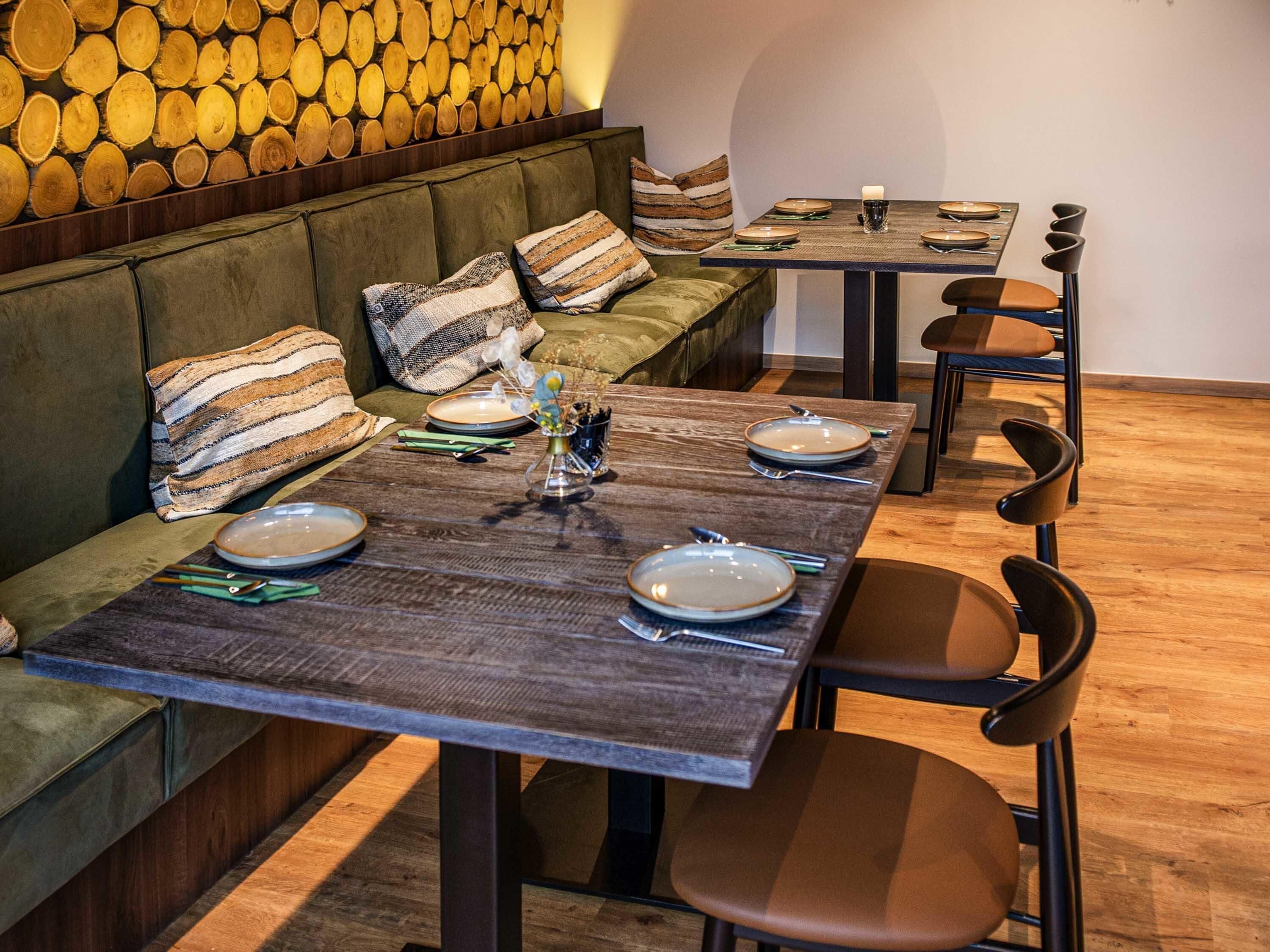 A dining area with a wooden table set for four, accompanied by a sofa and chairs.