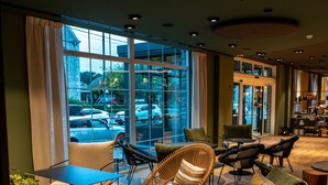 Un intérieur moderne avec des espaces aménagés pour s’asseoir, une table basse et une vue sur la rue grâce à de grandes fenêtres.