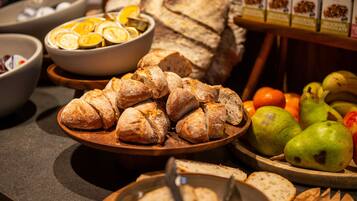 Un bufé con pan en rodajas, frutas cítricas y una hogaza de pan.