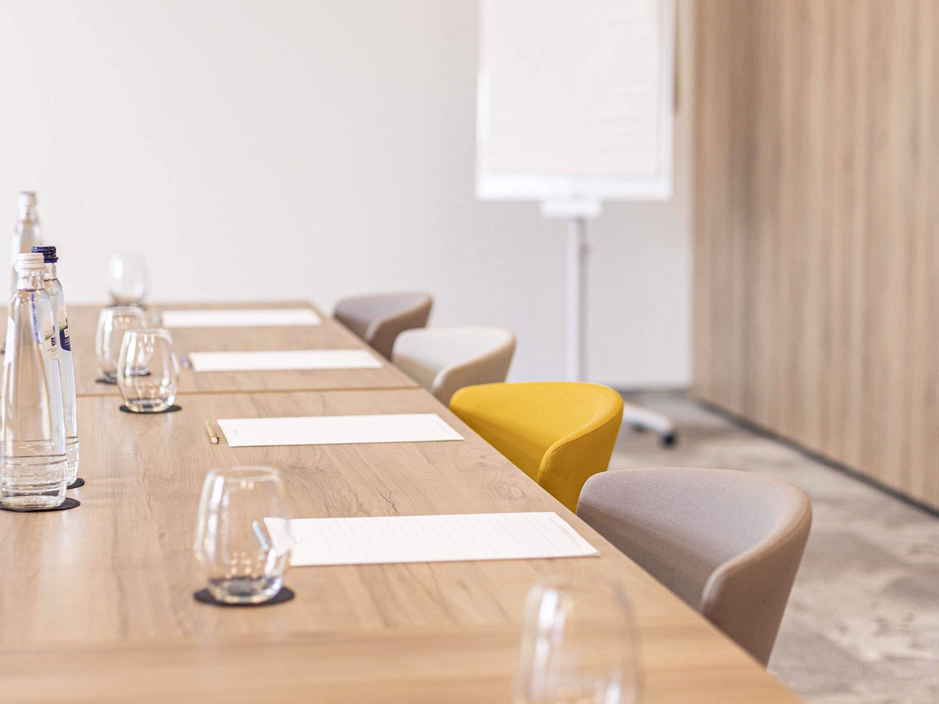 A conference room with a long table, chairs, water bottles, and glasses.