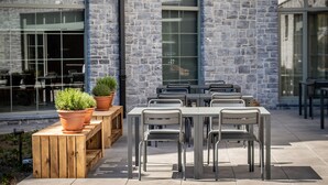 Un espace extérieur aménagé pour les repas, avec des murs en pierre, des bancs en bois et des chaises en métal.