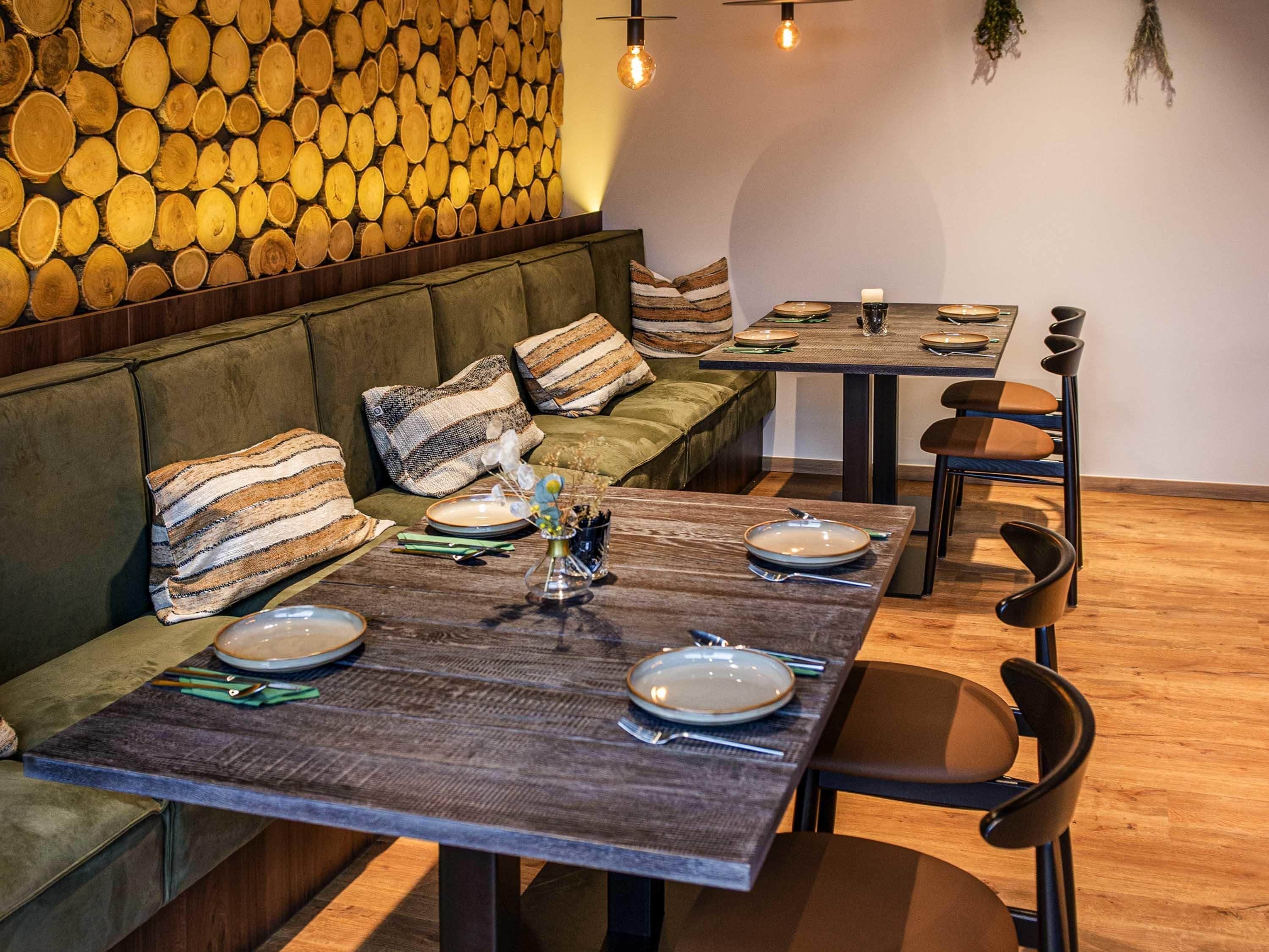 Un comedor con una pared de madera, un sofá con cojines a rayas y una mesa preparada para cuatro.