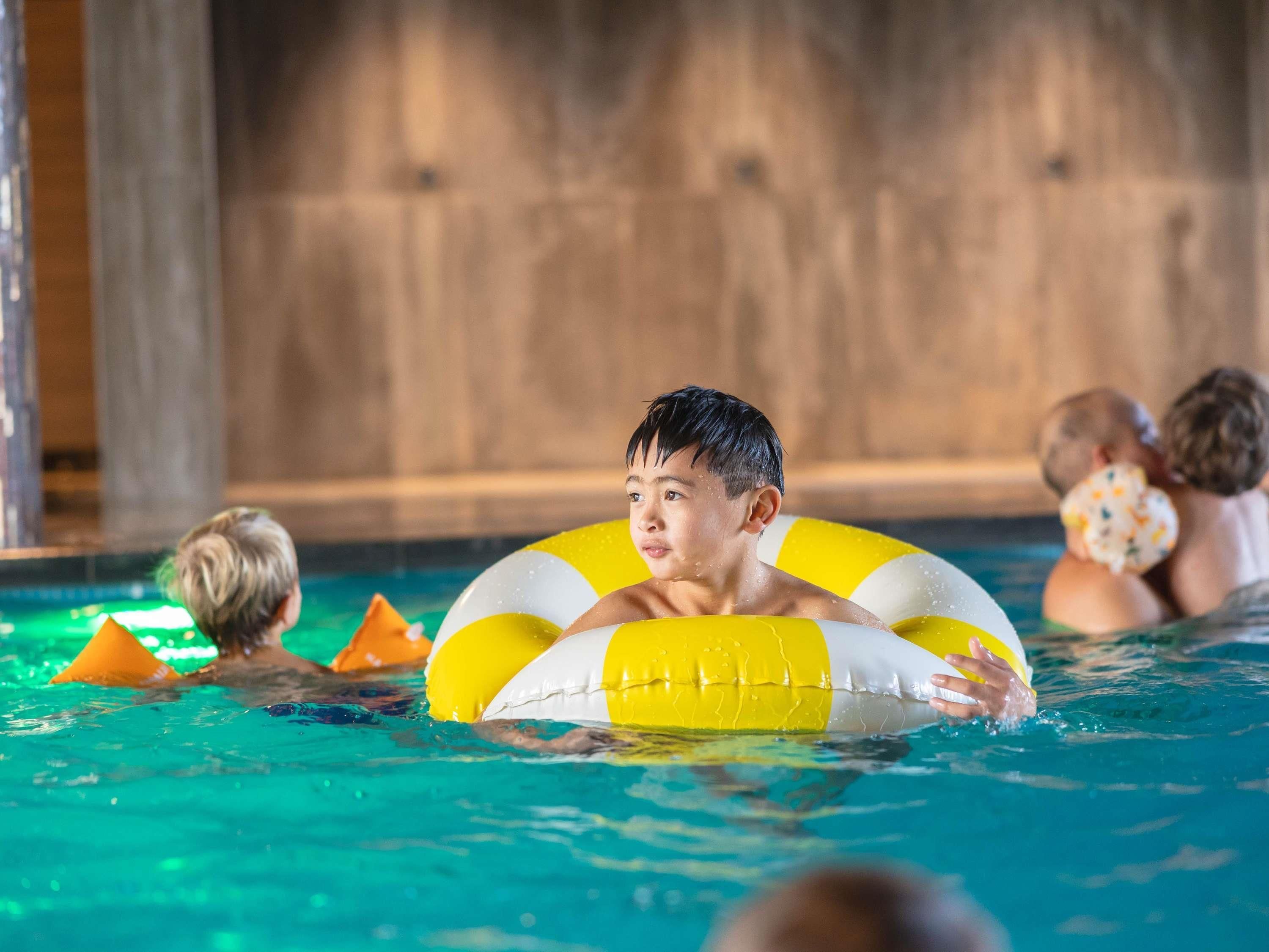 Una piscina con gente usando flotadores.
