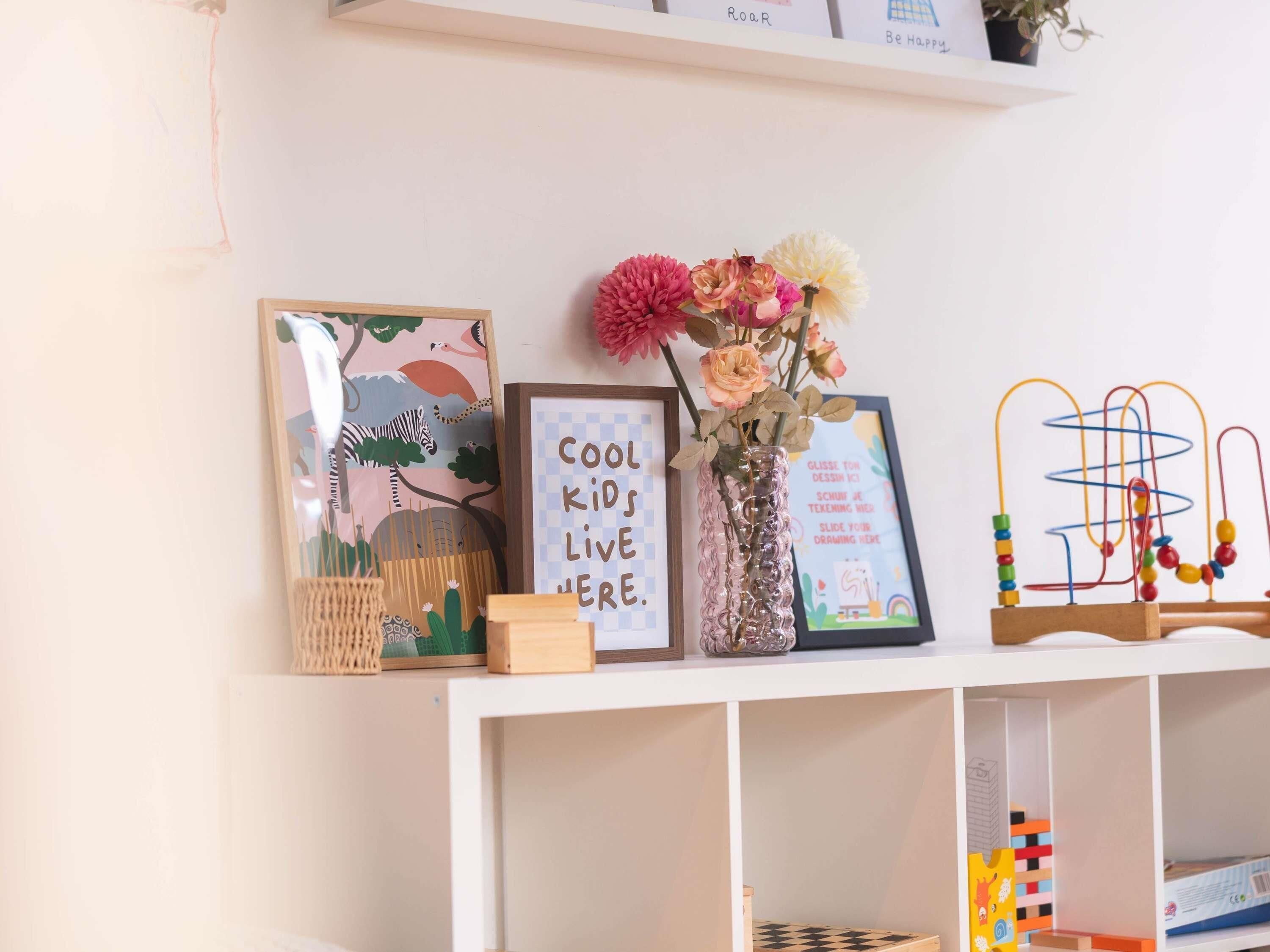 A shelf with various items including a framed picture with text, a vase with flowers, and a beaded abacus.