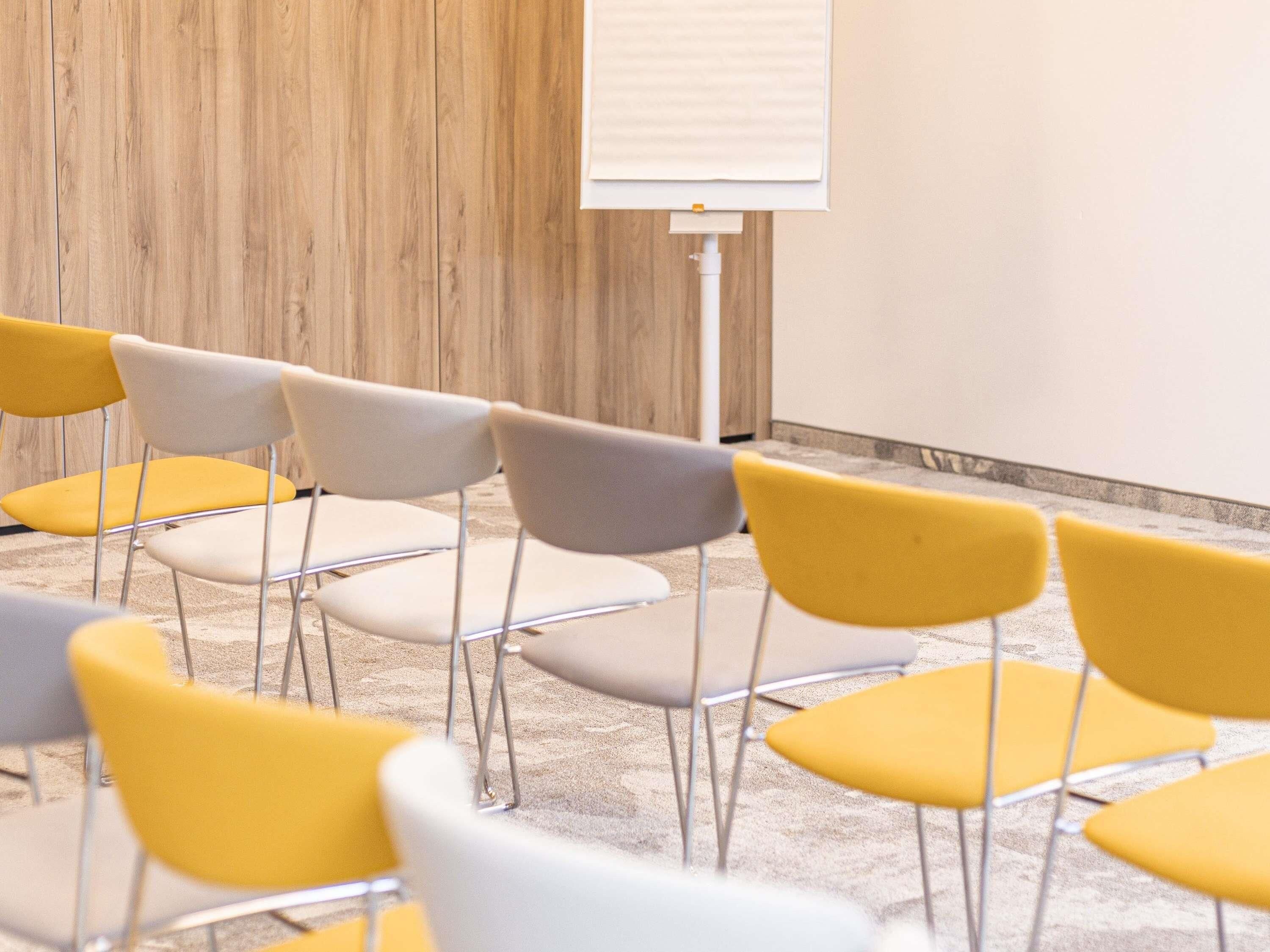 Une salle de conférence équipée d’un tableau blanc, de rangées de chaises et d’un sol recouvert de moquette.