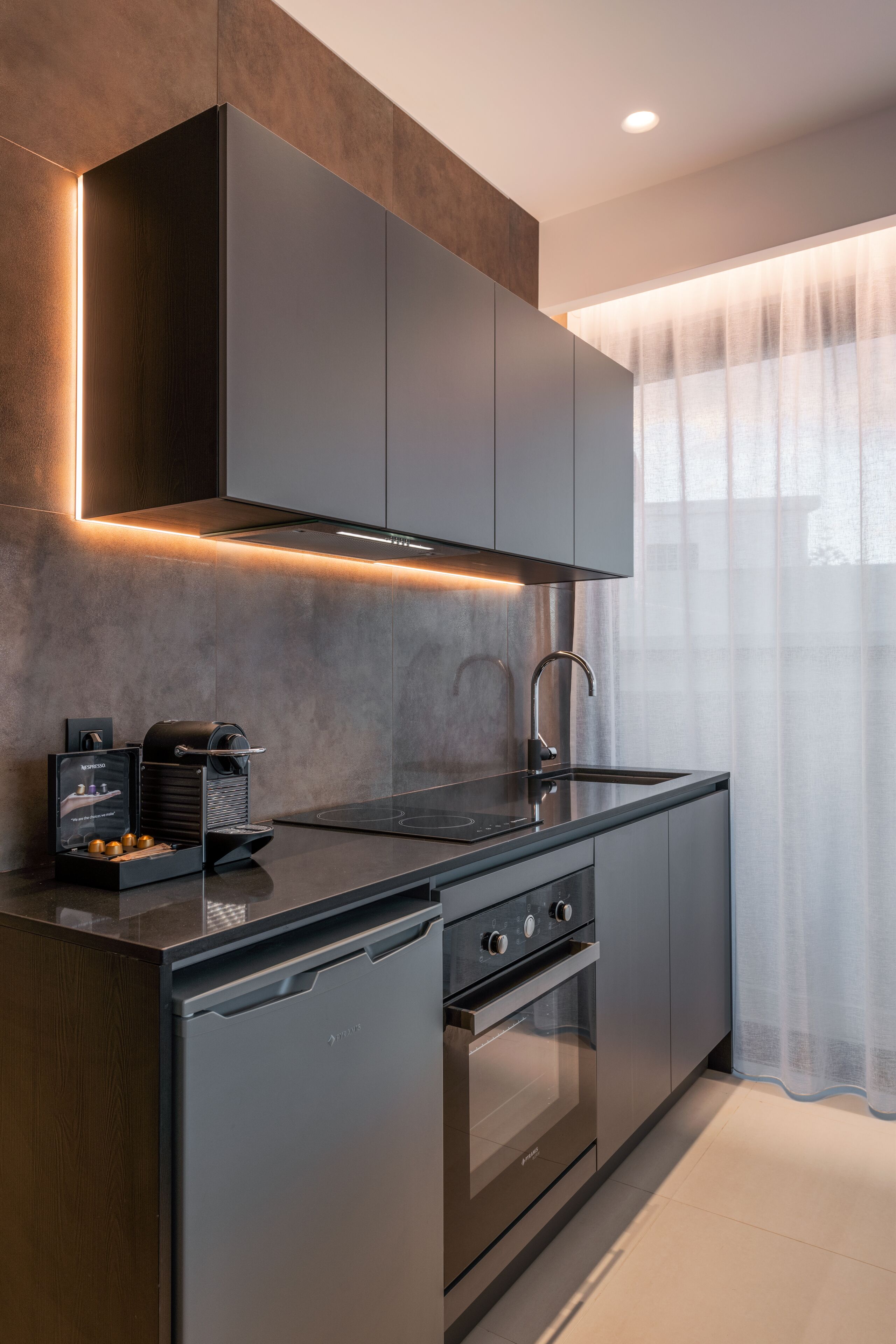 Een moderne keuken met een ingebouwde oven, een spoelbak en een koffieapparaat.