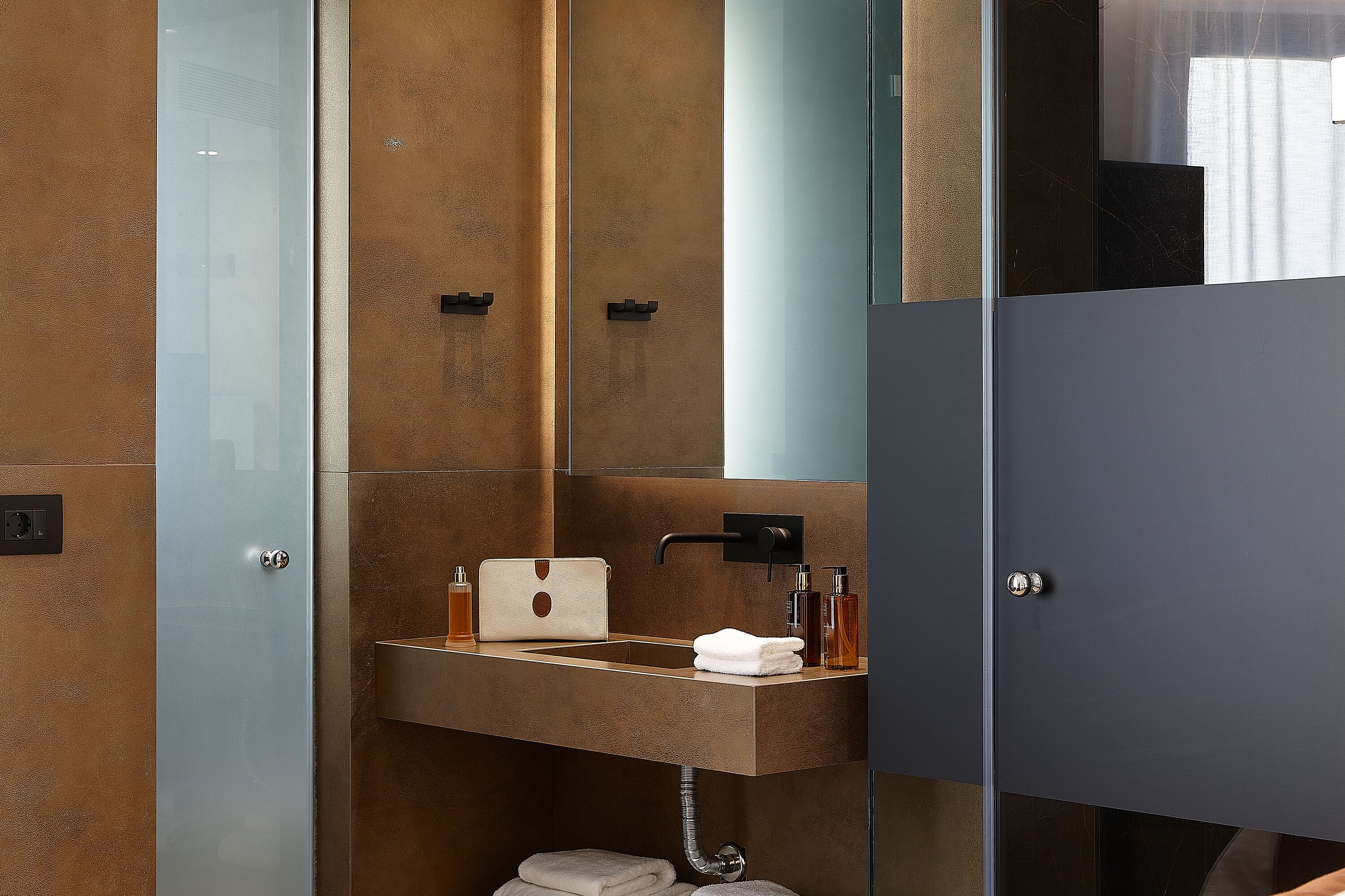 Un baño moderno con cabina de ducha de vidrio, lavamanos empotrado con una toalla y un espejo encima.