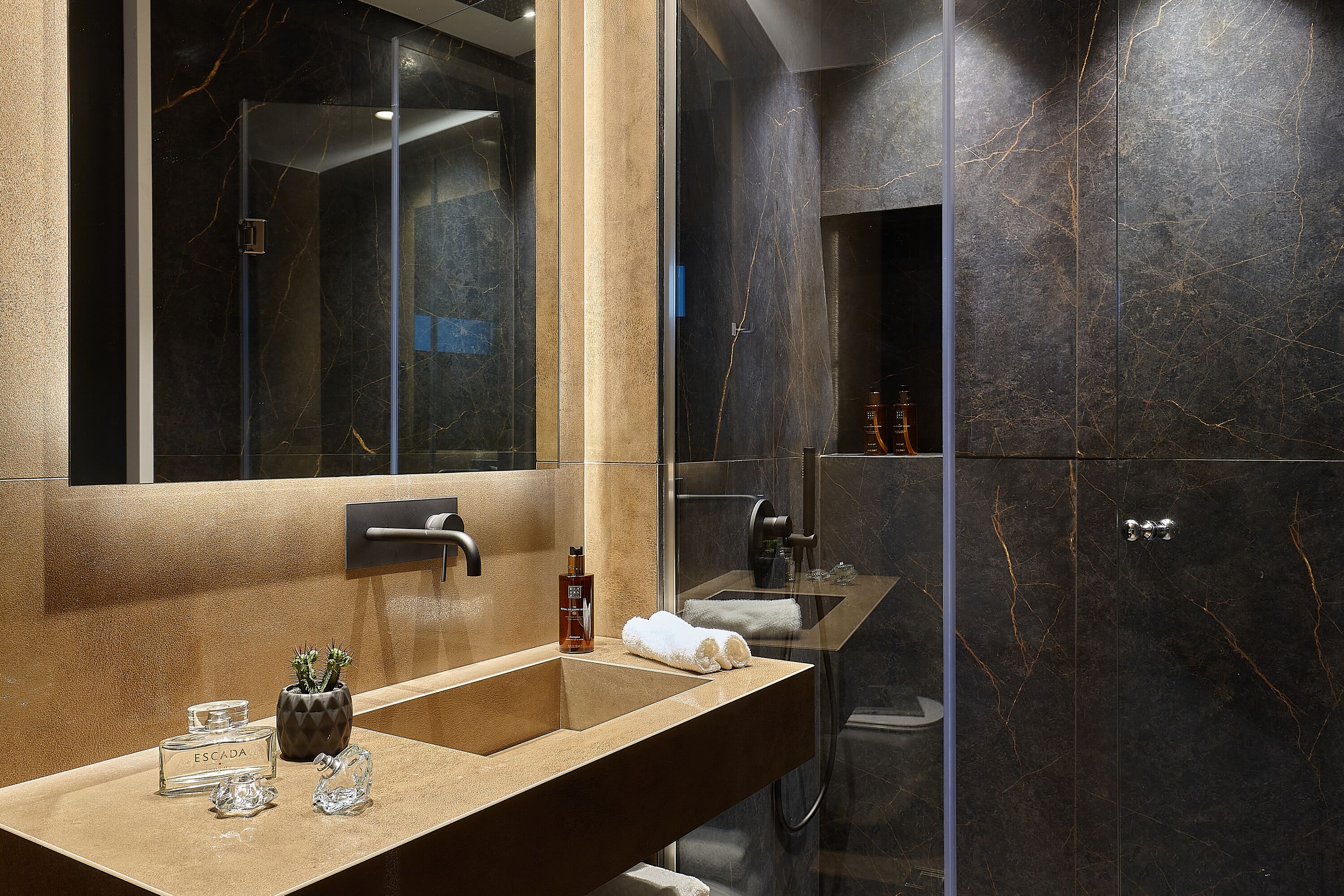A modern bathroom with a large mirror, a sink, and a shower area.