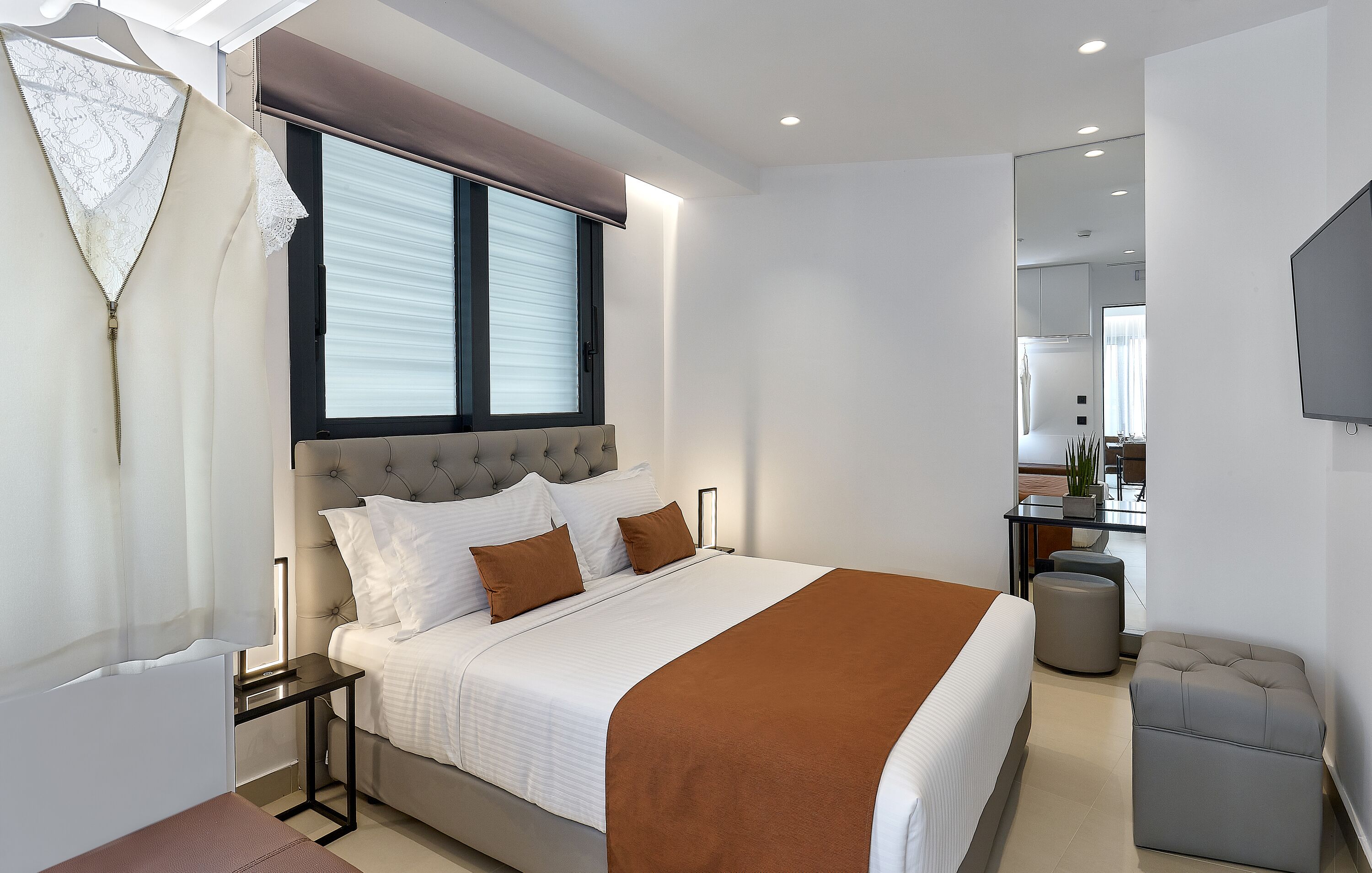 A modern bedroom with a large bed, bedside tables, a dresser, and a TV.