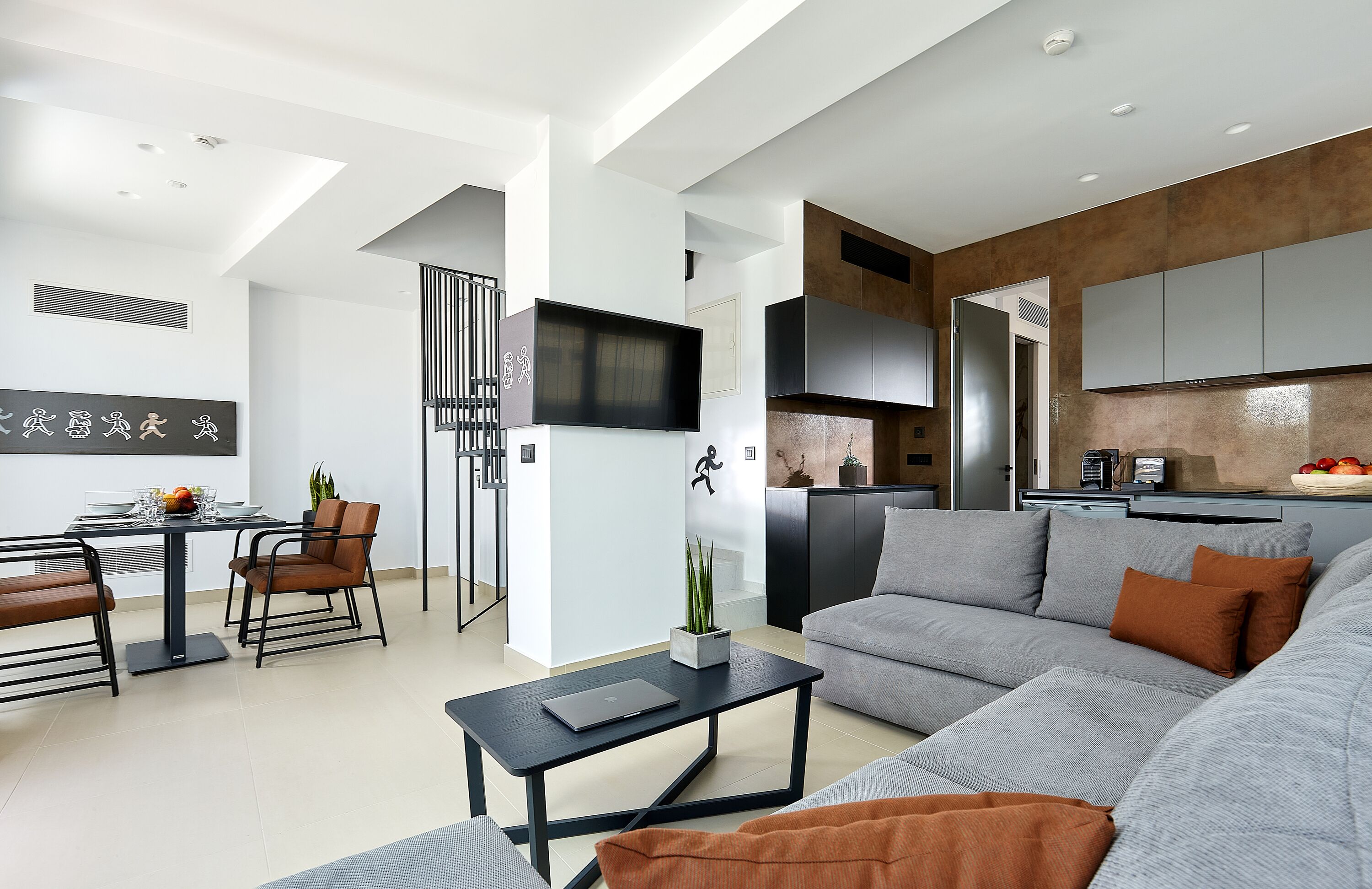 Una sala de estar moderna con un sofá gris, una mesa de centro negra y un comedor con mesa y sillas.