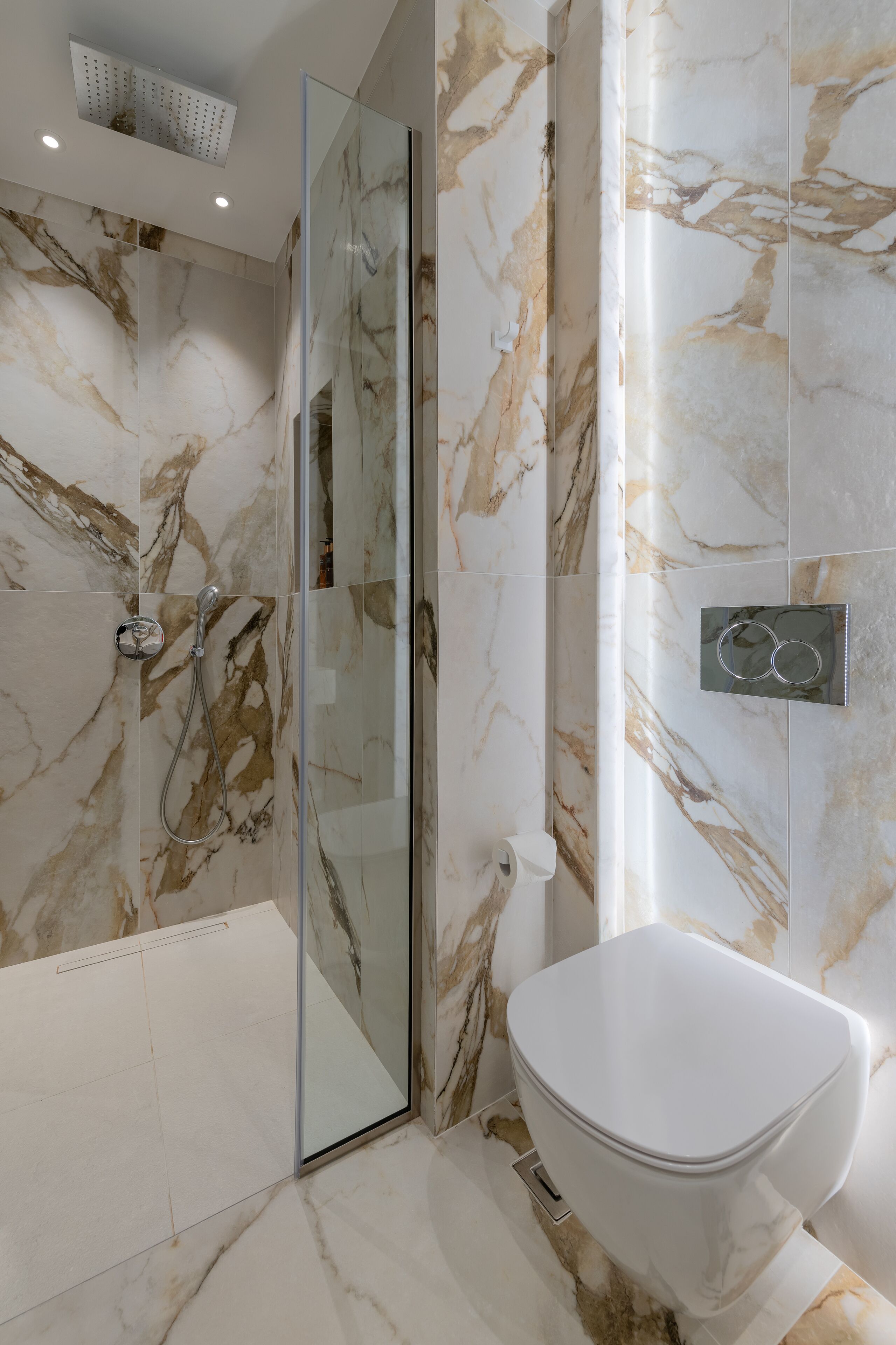 Une salle de bain moderne avec une douche à parois de verre, des toilettes blanches et des murs à motifs de marbre.