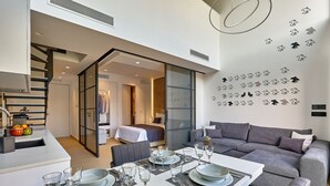 Um interior moderno com área de refeições, um sofá e uma escada que leva a um quarto.