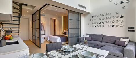 Un interior moderno con comedor, sofá y escalera que lleva a un dormitorio.